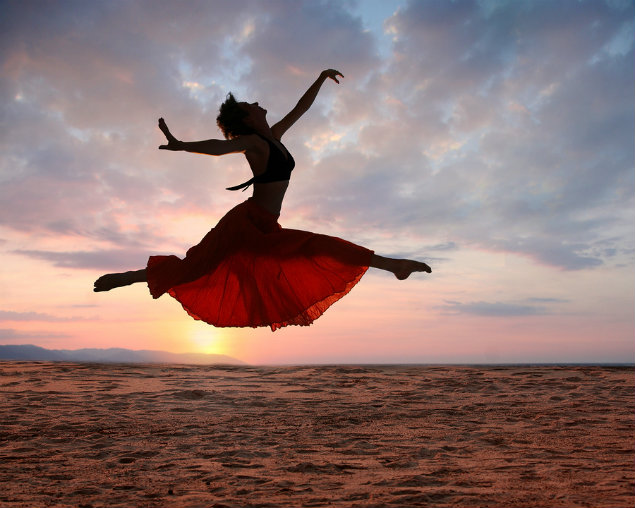 Dramatic image of a woman jumping above the ocean at sunset, silhouette